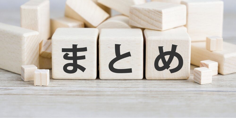 木製のブロック3つが並び、それぞれに「ま」「と」「め」と黒文字で書かれている様子。背後には同系の無地ブロックが積まれている